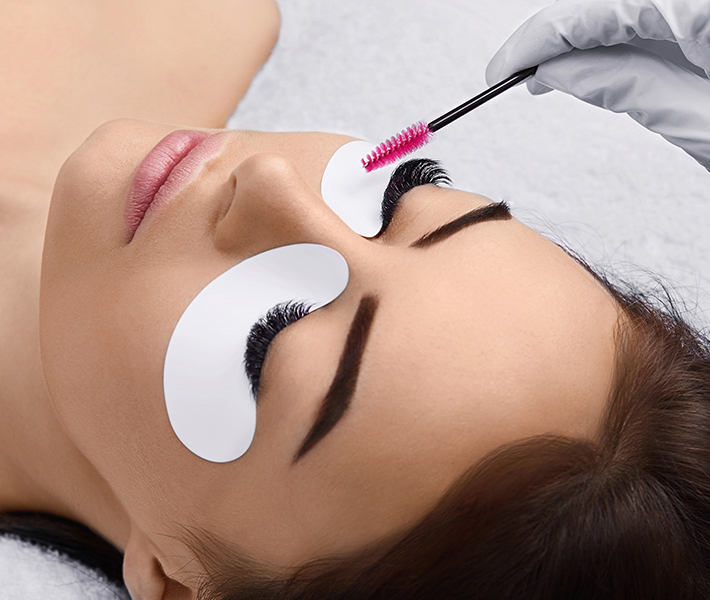 A finished lash set being brushed through with a spoolie, under-eye pad in place